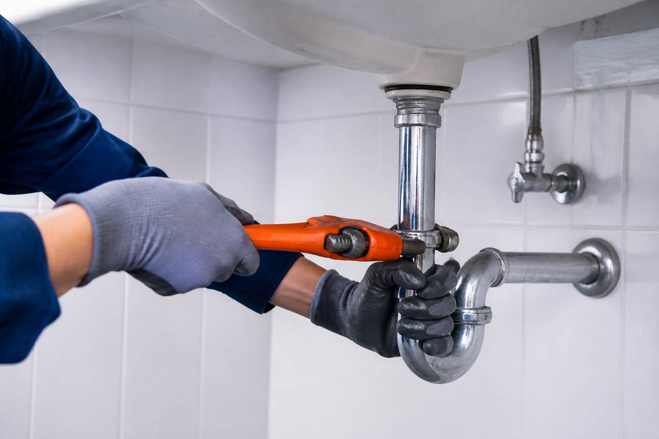 Plumber repairing pipework under a sink